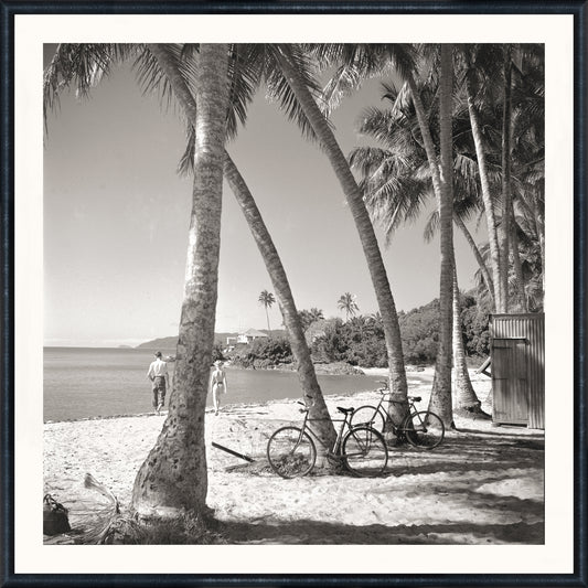 Black-and-white coastal photograph of a beach scene with palm trees, bicycles, and beachgoers at Mastry’s Art Shop in St. Petersburg, Florida